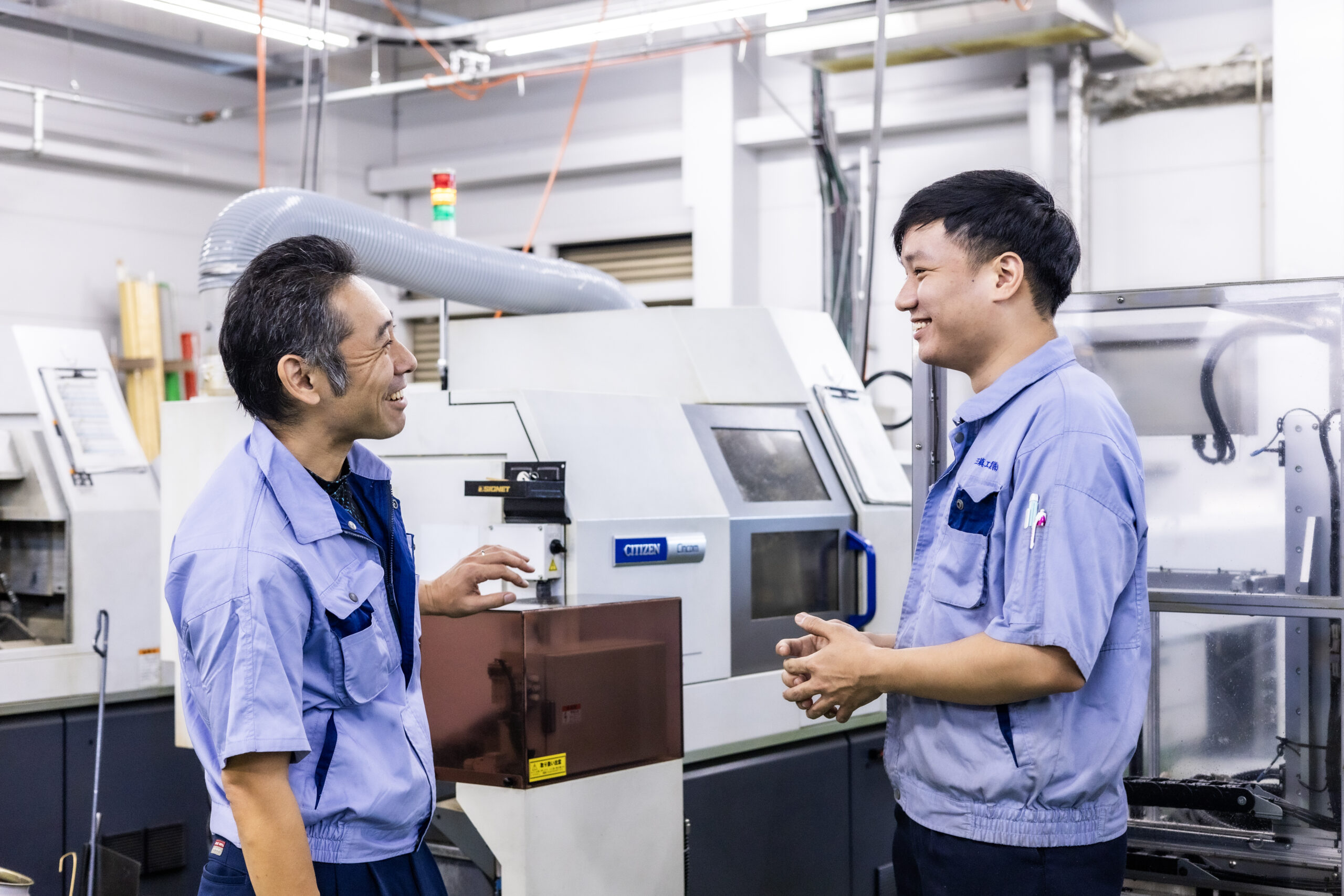 Our staff talking in front of a lathe